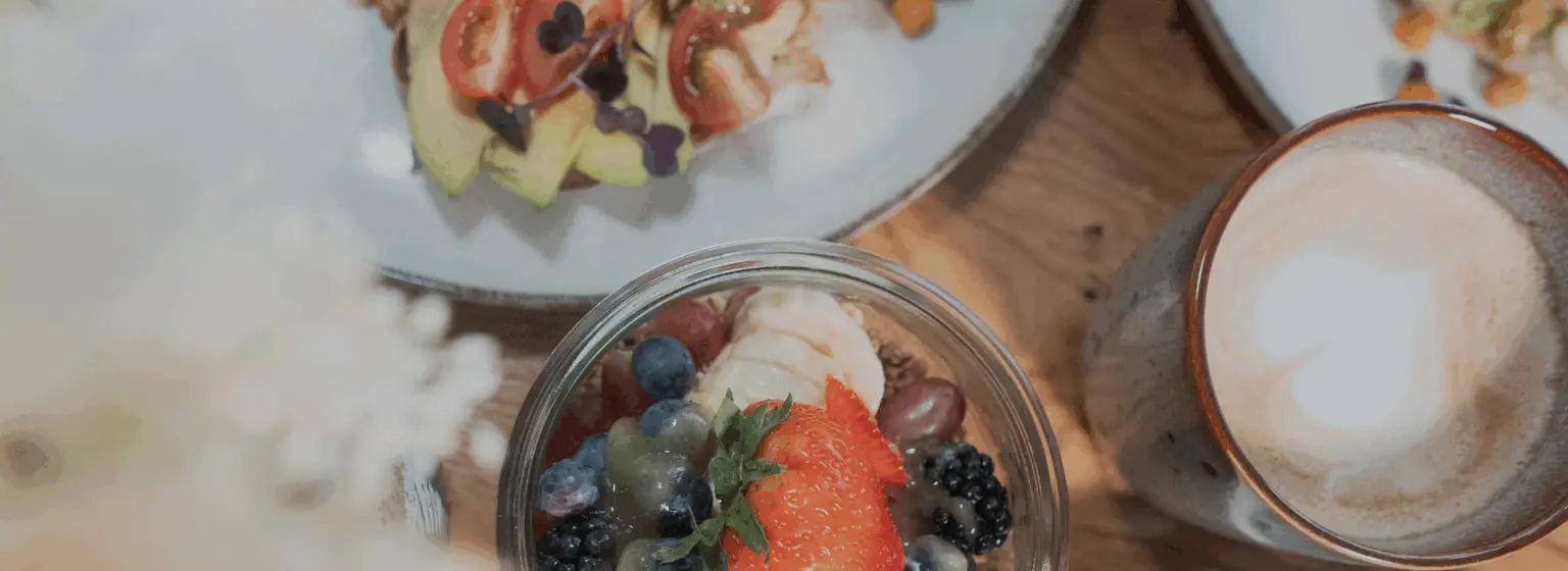 Frühstückstisch mit Joghurt-Bowl, Beeren und Cappuccino